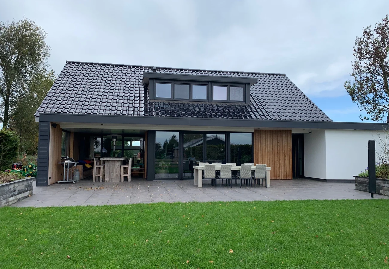 Afgeronde aanbouw met grote schuifpuien en houten gevelbekleding, aansluitend op de bestaande woning in Spakenburg