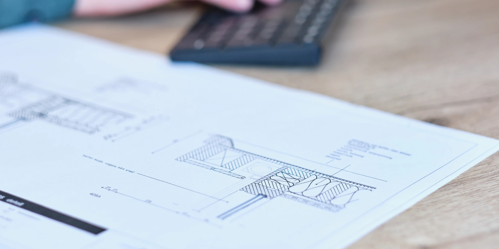 Bouwtekening met detailaansluiting van een uitbouw op een bureau, naast een toetsenbord tijdens het ontwerpproces bij AanbouwMaximaal