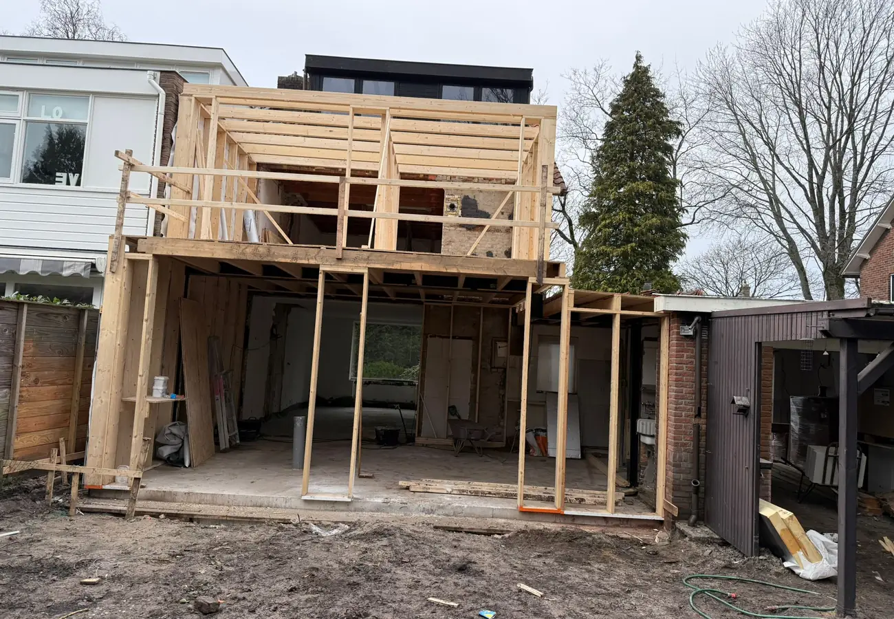 Houten skeletbouw van een aanbouw voor een thuiskantoor, met de constructie van vloer, wanden en dak nog volledig in het zicht vóór het metselwerk.