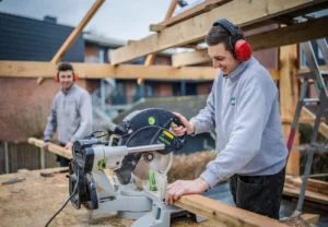 Bouwvakkers van Ter Beek Bouw zagen constructiehout tijdens de bouw van een houten aanbouw